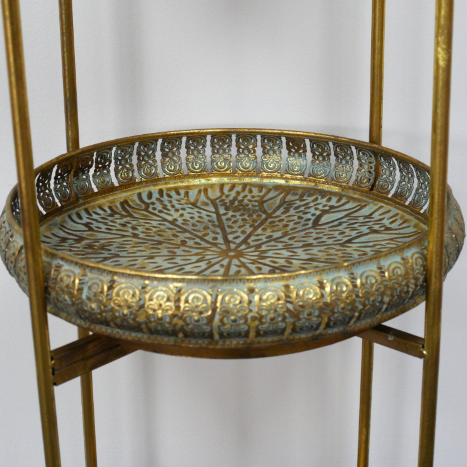 Decorative metal tray on a stand with intricate patterns against a plain background