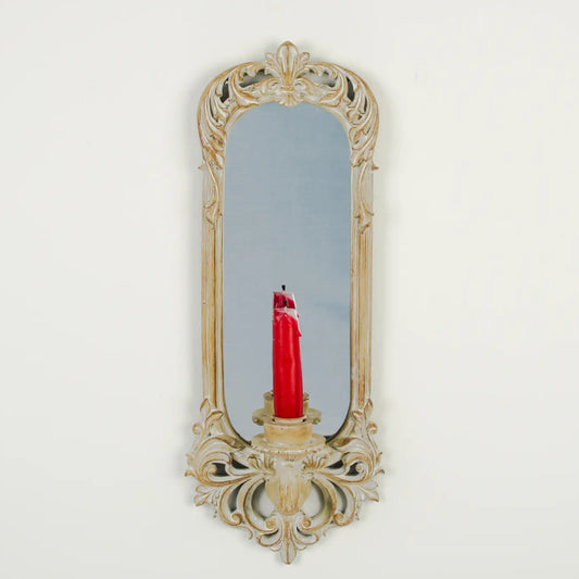 Decorative wall mirror with a candle holder on a white background