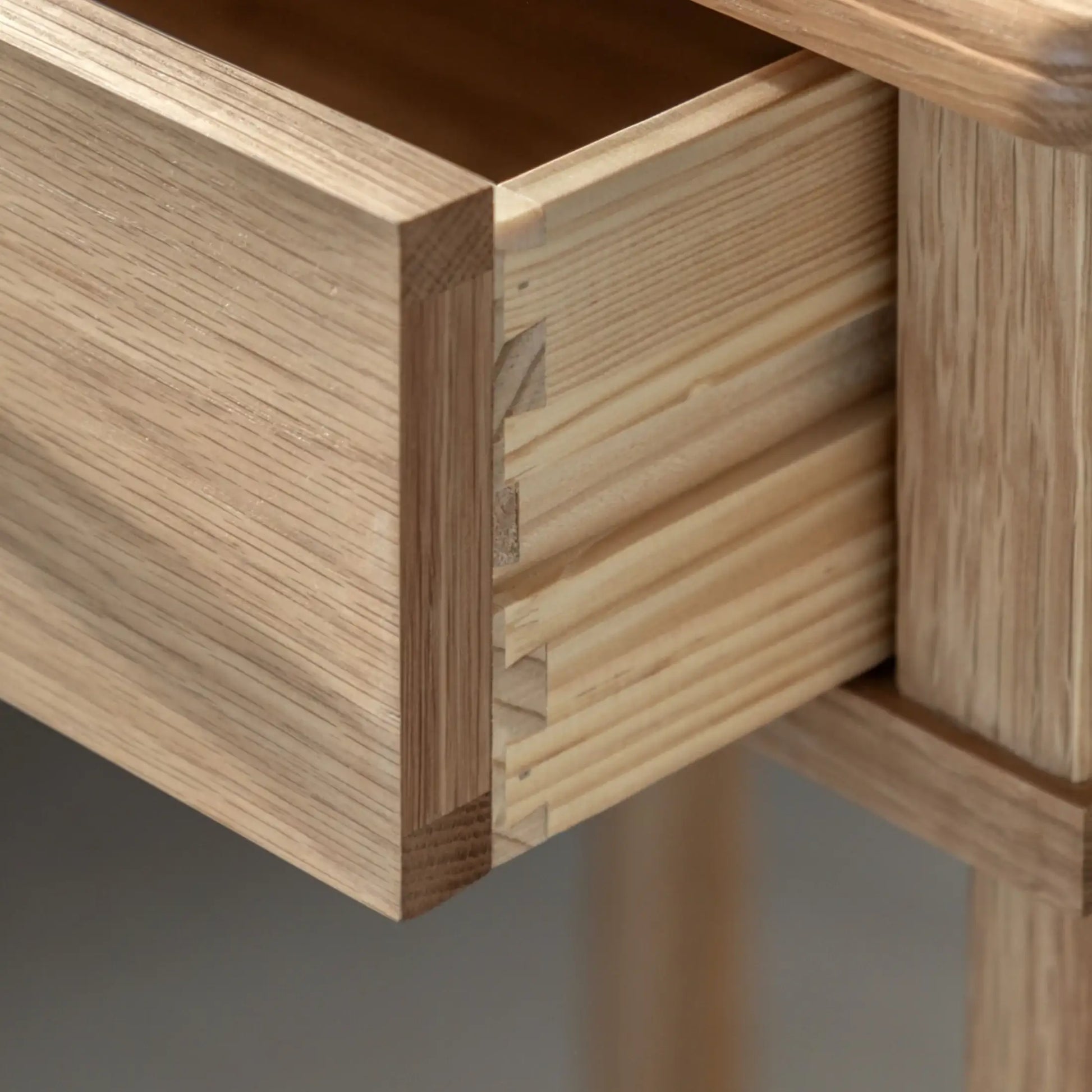 Close-up of a wooden drawer with dovetail joint on a gray background