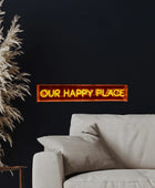 Neon sign reading 'Our Happy Place' above a sofa with decorative pampas grass.