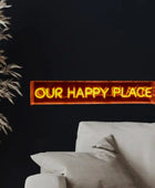 Neon sign reading 'OUR HAPPY PLACE' in a living room setting with a couch and decorative plant.