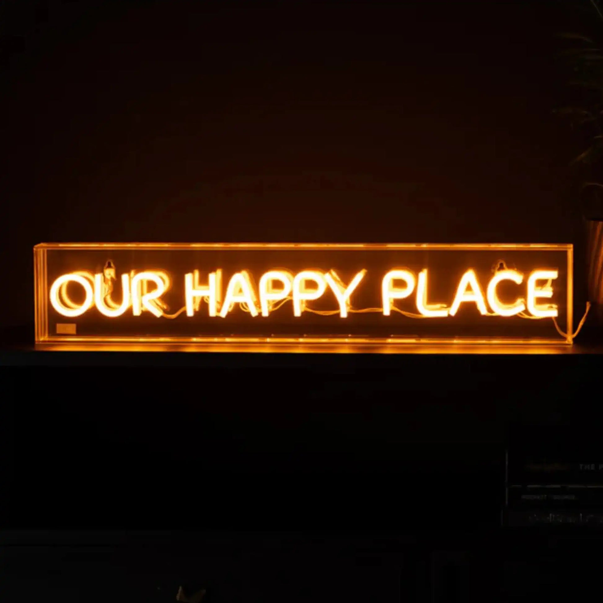 Neon sign with 'OUR HAPPY PLACE' text on a dark background