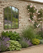 Decorative window with metal grille on a stone wall with greenery outside