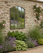 Garden scene with stone wall, mirror, and flowering plants