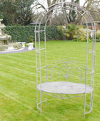 Decorative metal garden arch with round table on a grassy lawn