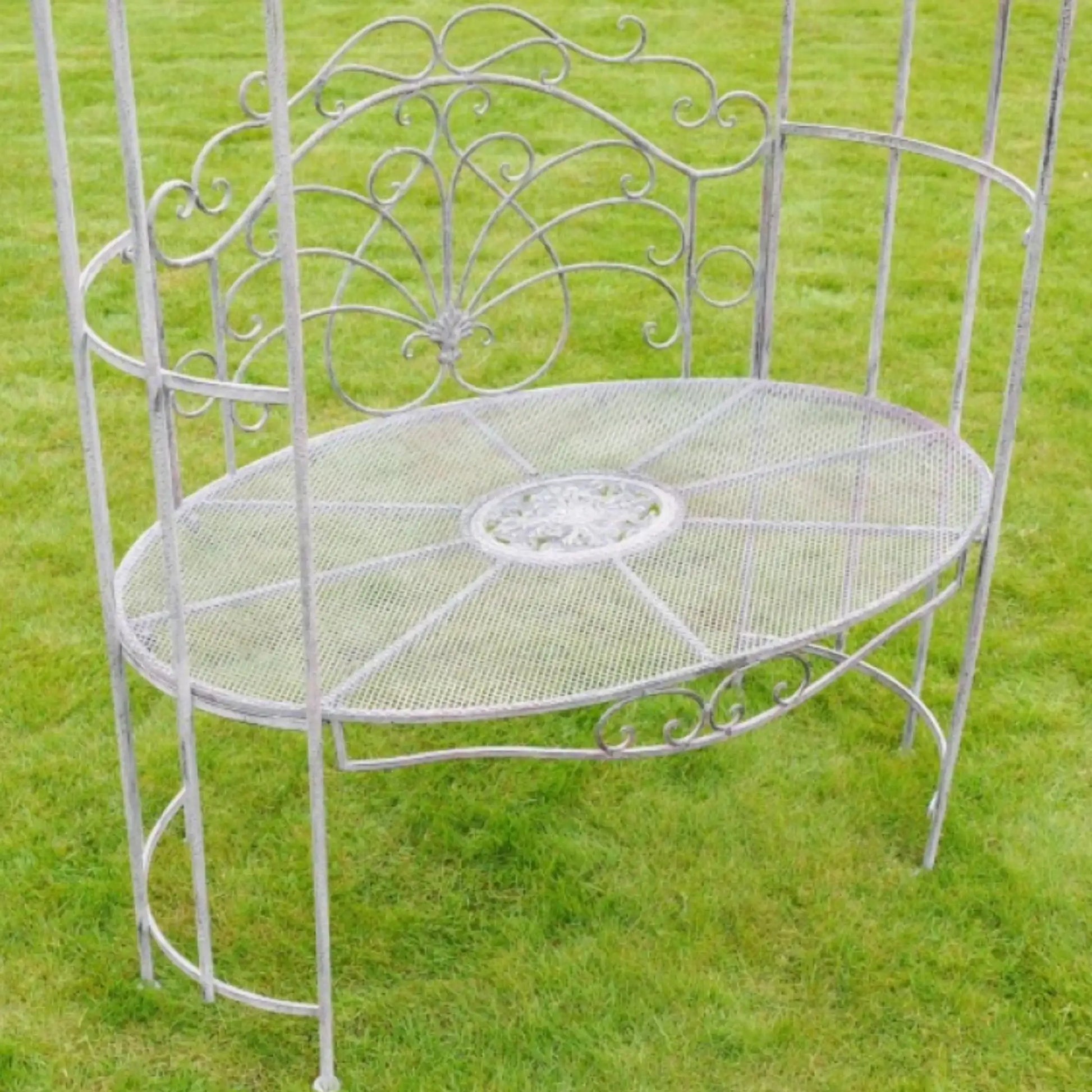 Decorative metal bench with intricate designs on a grassy background