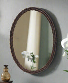 Oval mirror with a decorative brown frame on a white background