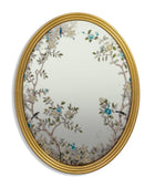 Decorative oval mirror with floral and bird design in a gold frame on a white background