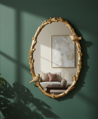 Gold-framed mirror on a green wall with a plant and sofa reflection