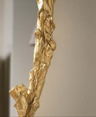 Gold leafed decorative branch against a neutral wall