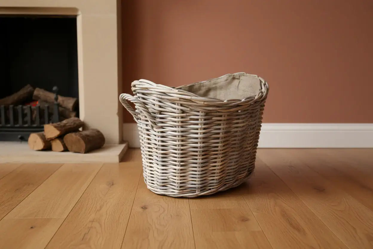 Wicker basket on a wooden floor with a fireplace and logs in the background