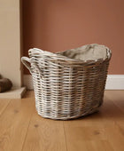 Wicker laundry basket on a wooden floor with a fireplace in the background
