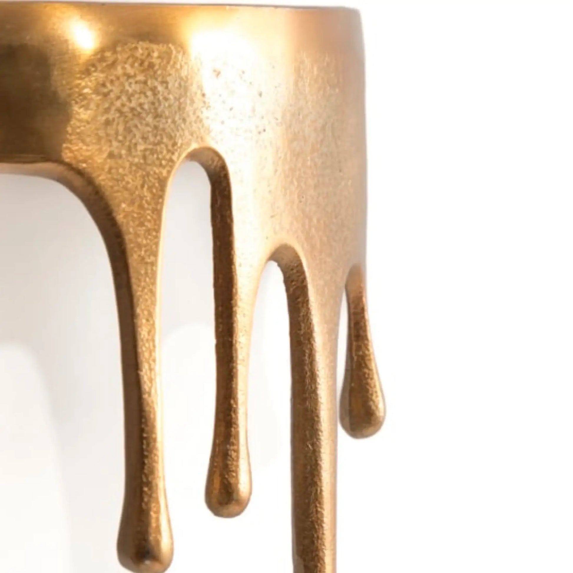 Close-up of a gold-colored object with dripping design on a white background