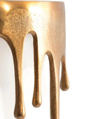 Close-up of a gold-colored object with dripping design on a white background