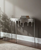 Decorative console table with books against a wall in a room with a plant and rug.