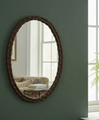 Oval mirror with decorative brown frame on a white background