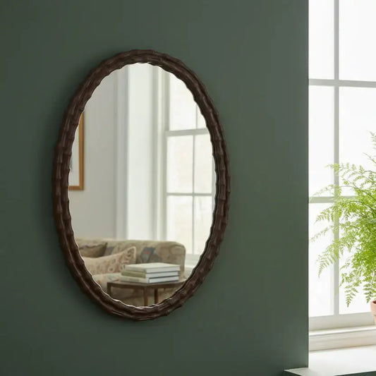 Oval mirror with decorative brown frame on a white background