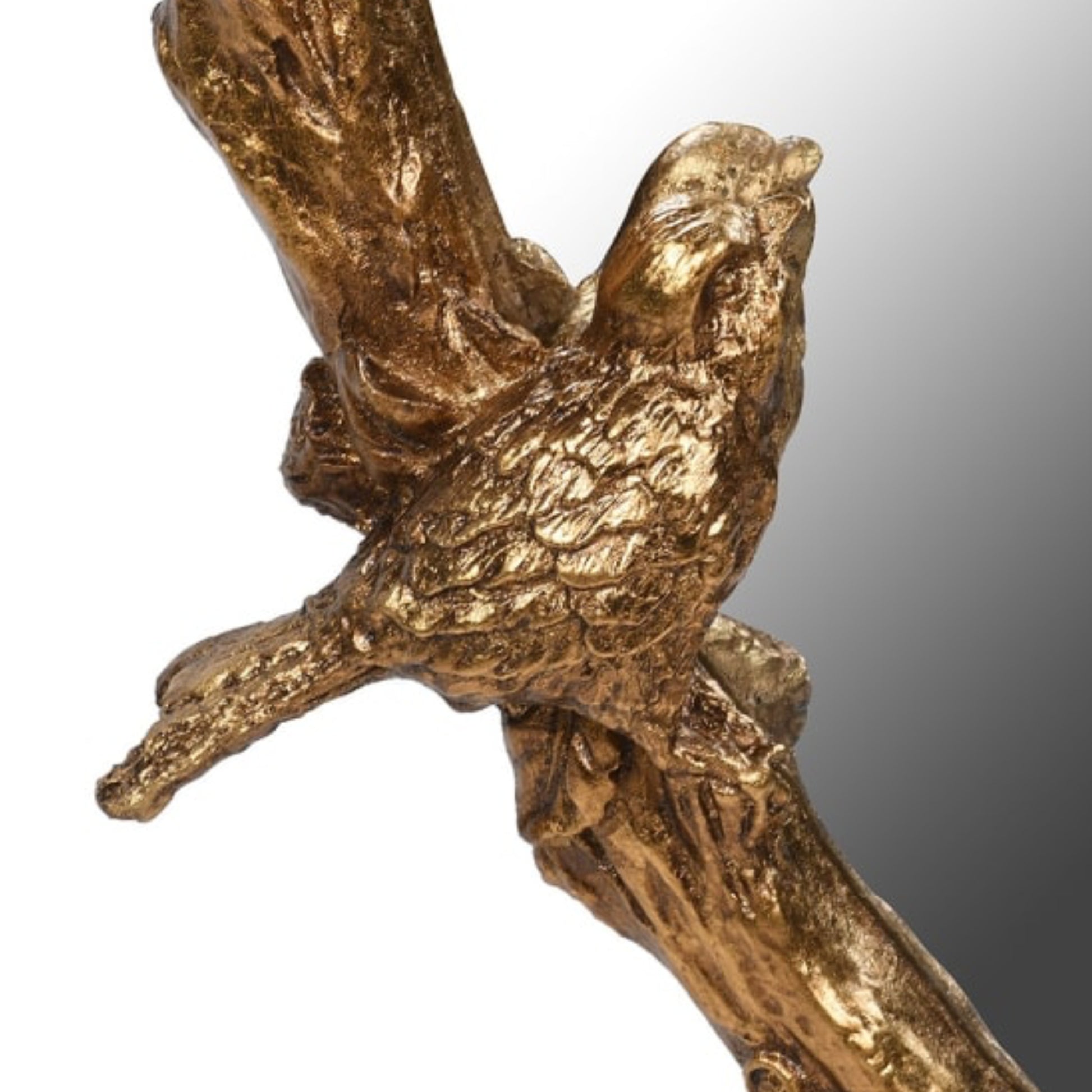 Bronze sculpture of a bird perched on a branch against a gradient background