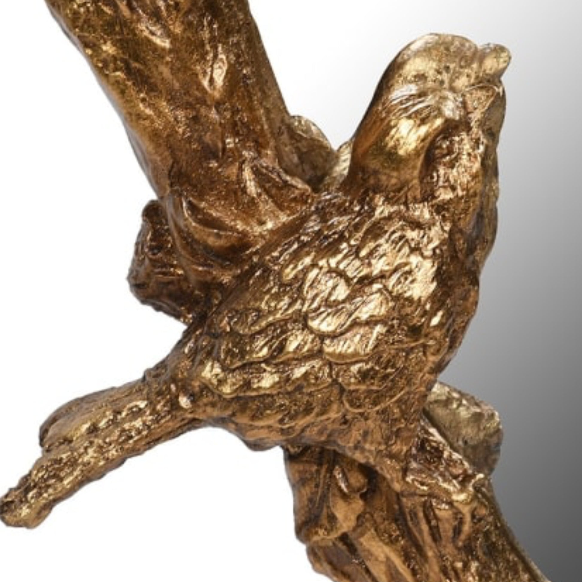 Bronze sculpture of a bird perched on a branch against a white background