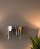 Decorative wall sconce with a plant and lamp in the background