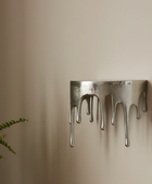 Metal wall art with a dripping design on a beige wall