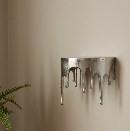 Metal wall art with a dripping design on a beige wall