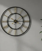 Large wall clock with gold Roman numerals on a gray wall.