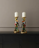 Decorative candle holders with toucan designs and candles on a white background