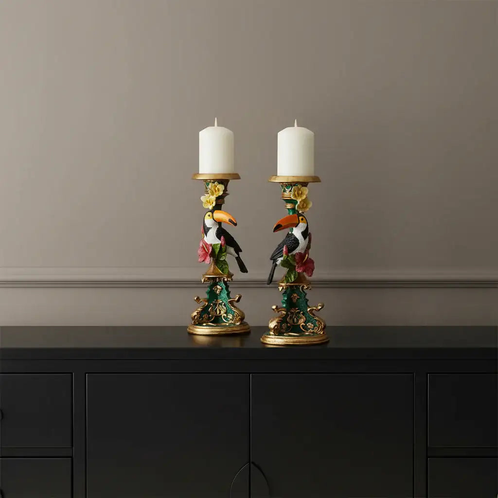 Decorative candle holders with toucan designs and candles on a white background