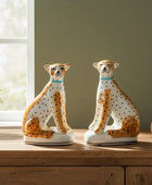 Two ceramic cheetah figurines on a wooden surface with a window in the background