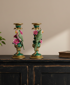 Decorative candle holders with birds and flowers on a wooden surface.