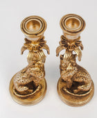 Pair of gold candle holders with animal designs on a white background