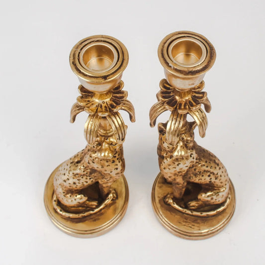Pair of gold candle holders with animal designs on a white background
