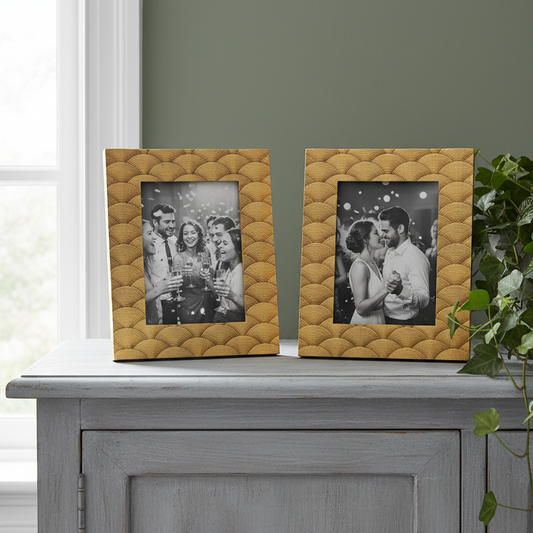 Two textured gold picture frames on a gray surface with photos inside.