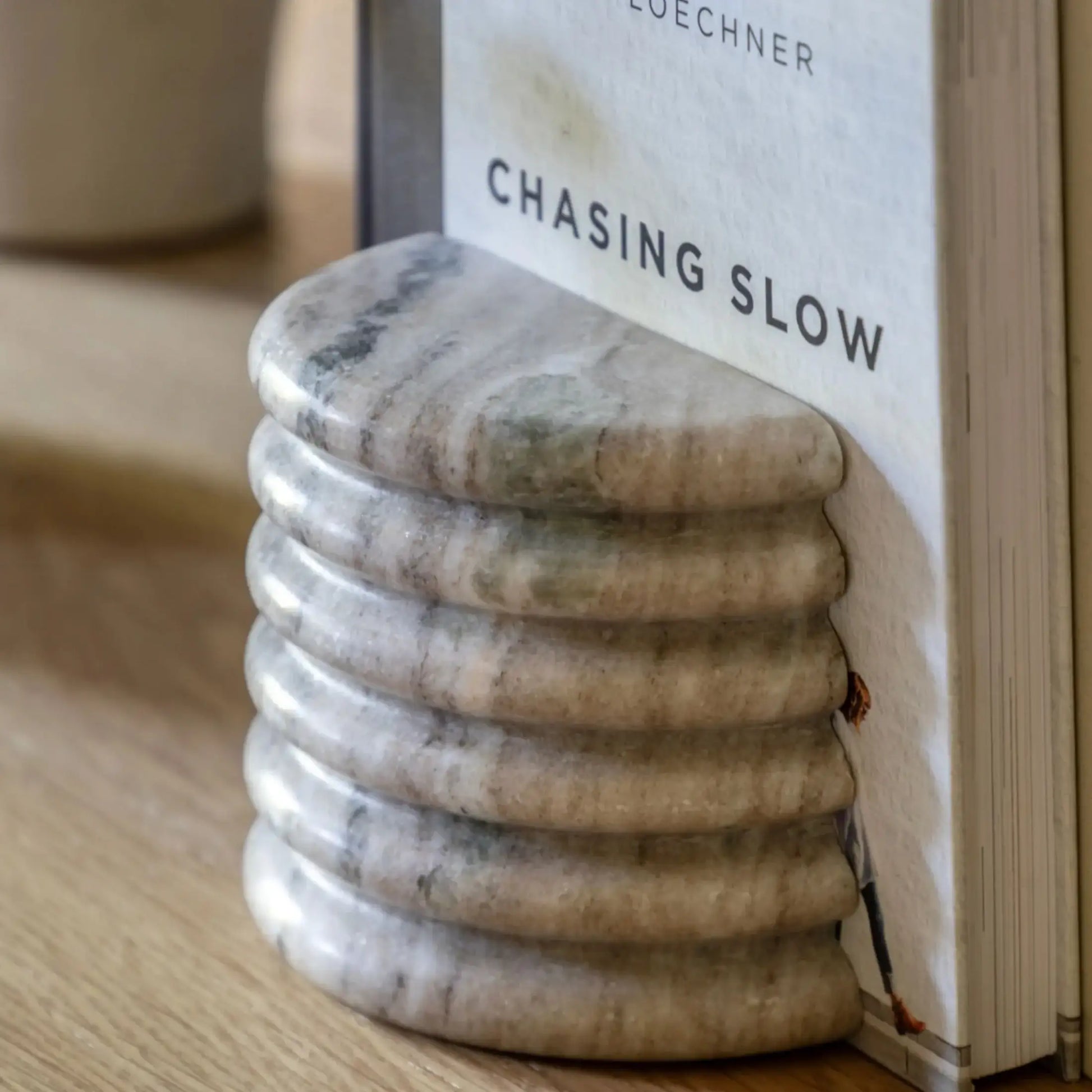 Marble stone stack with a book titled 'Chasing Slow' by Loehner on a wooden surface.