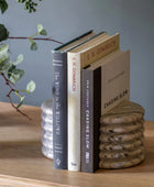 Stack of books on a wooden surface with a plant in the background