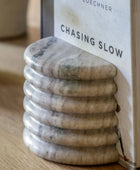Marble stone stack with a book titled 'Chasing Slow' by Loehner on a wooden surface.