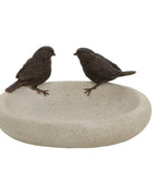 Two small bird figurines on a stone surface against a white background