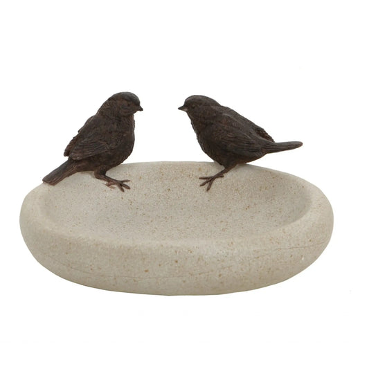 Two small bird figurines on a stone surface against a white background
