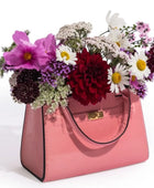 Pink handbag filled with a colorful bouquet of flowers on a white background