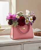 Pink handbag filled with flowers on a wooden surface