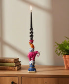 Decorative candle holder with books and a potted plant on a wooden surface.