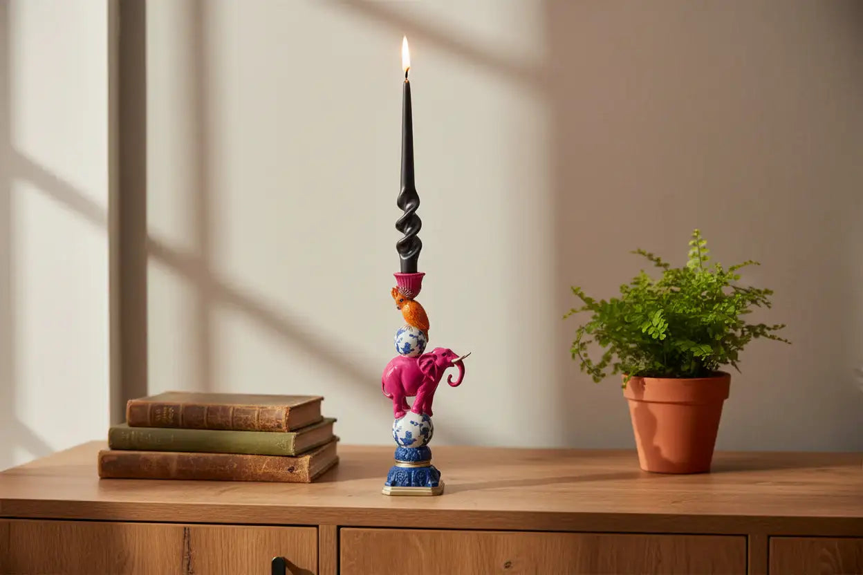 Decorative candle holder with books and a potted plant on a wooden surface.
