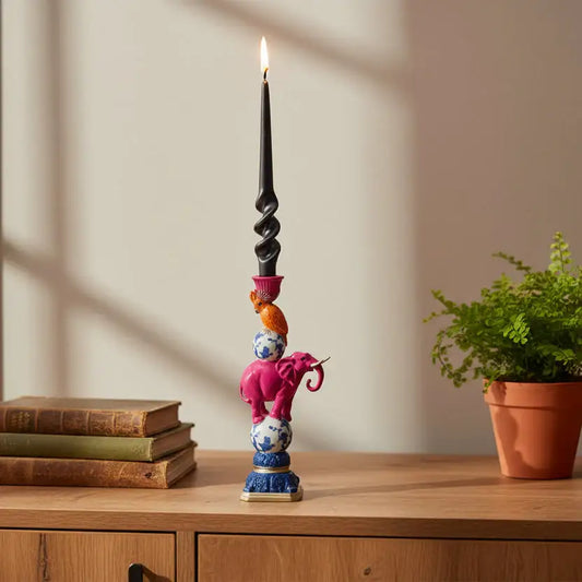 Decorative candle holder with colorful design on a wooden surface with books and a plant.