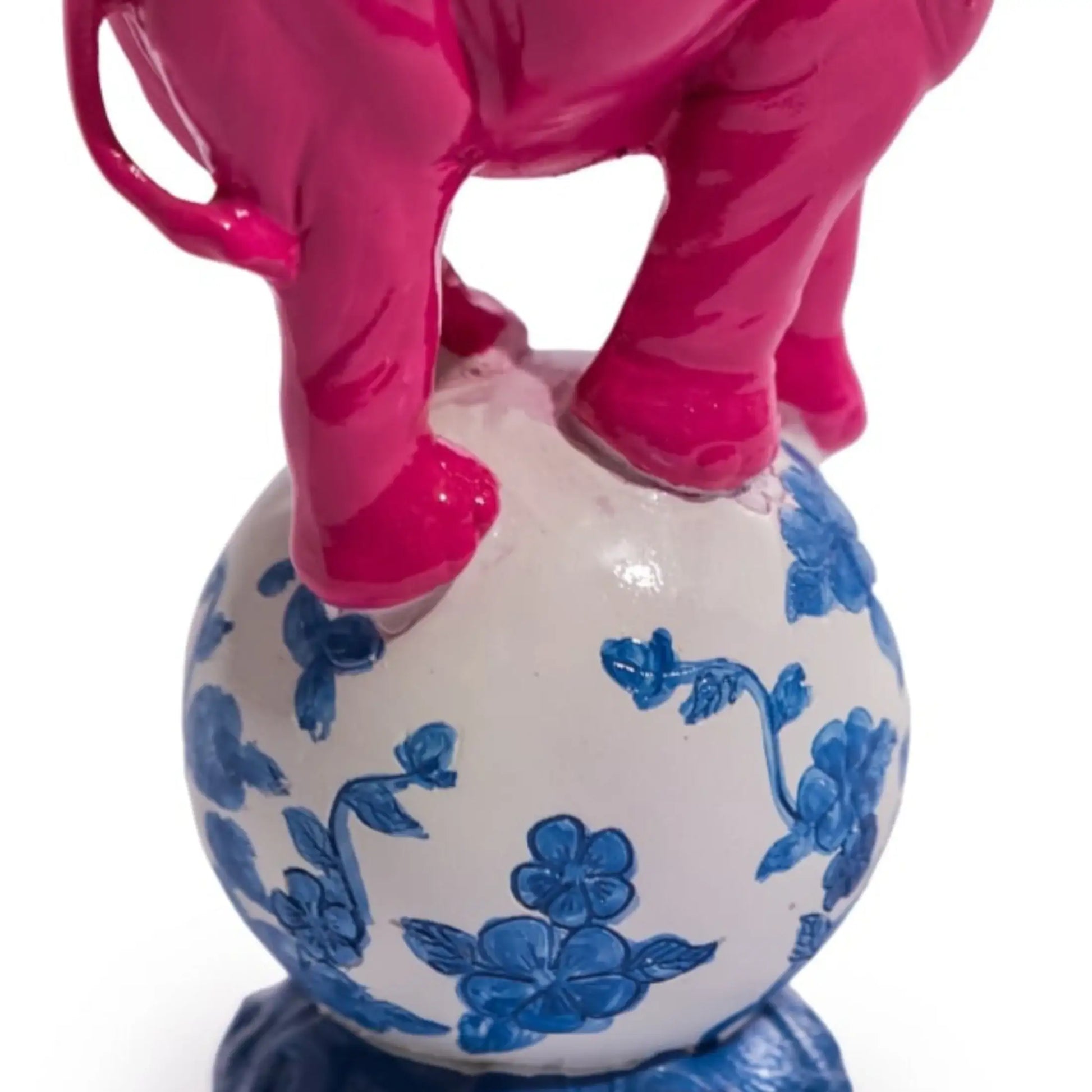 Pink elephant standing on a white vase with blue floral patterns on a white background