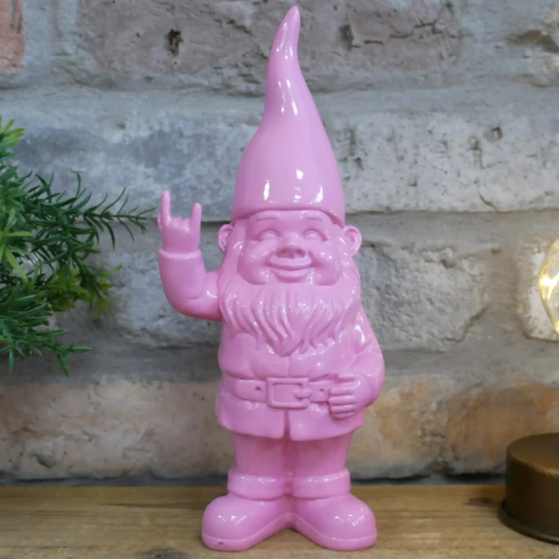 Pink garden gnome figurine with a stone wall background