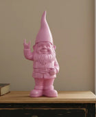 Pink gnome figurine on a wooden surface with a plain wall background