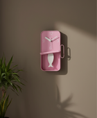 Pink wall clock with fish design on a brown wall
