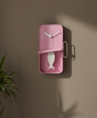 Pink wall clock with fish design on a brown wall