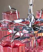 Close-up of a metallic chandelier with red glass shades against a neutral background